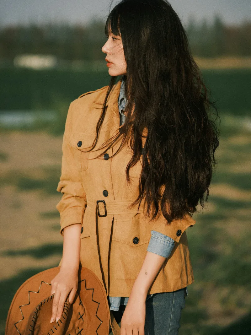 Tan suede coat styled with dark denim, back view in a field
