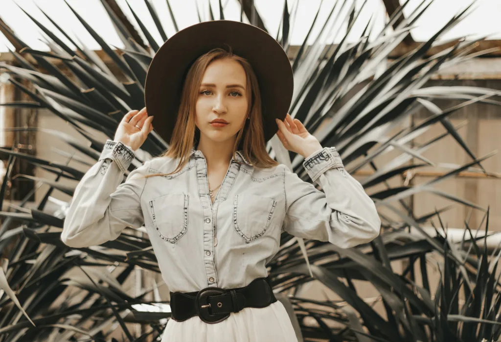 White pearl snap western shirt with a black belt and felt hat