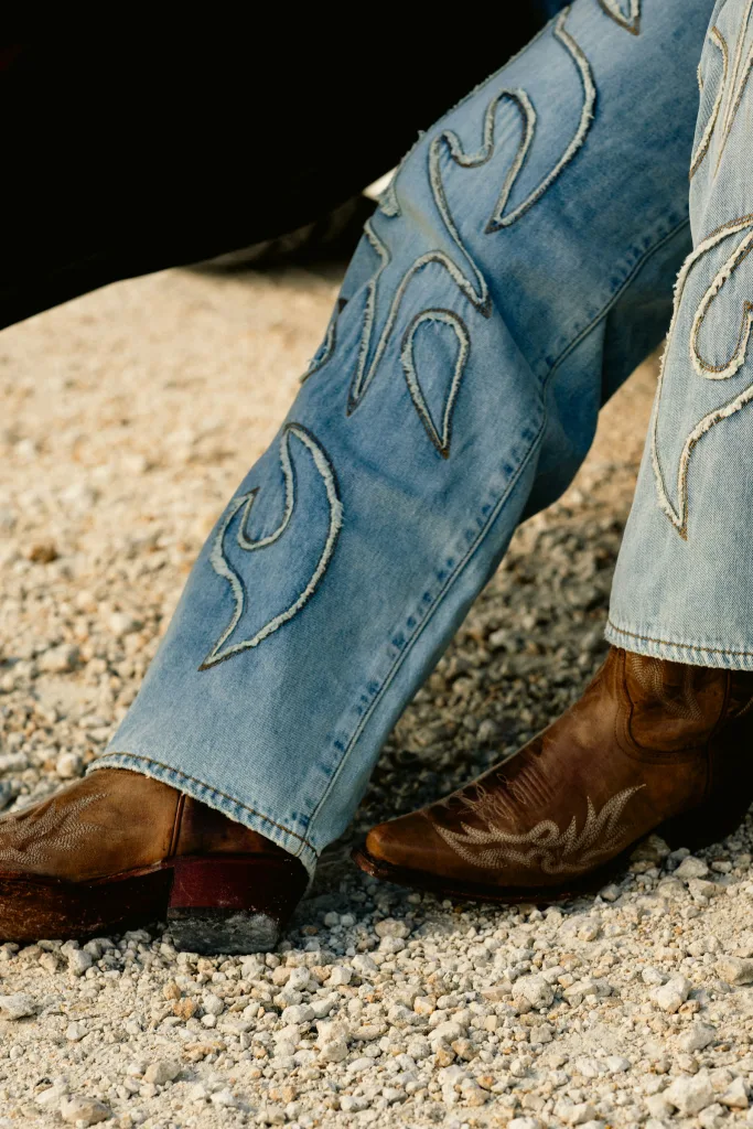 Embroidered boot-cut jeans stacked over tooled western boots