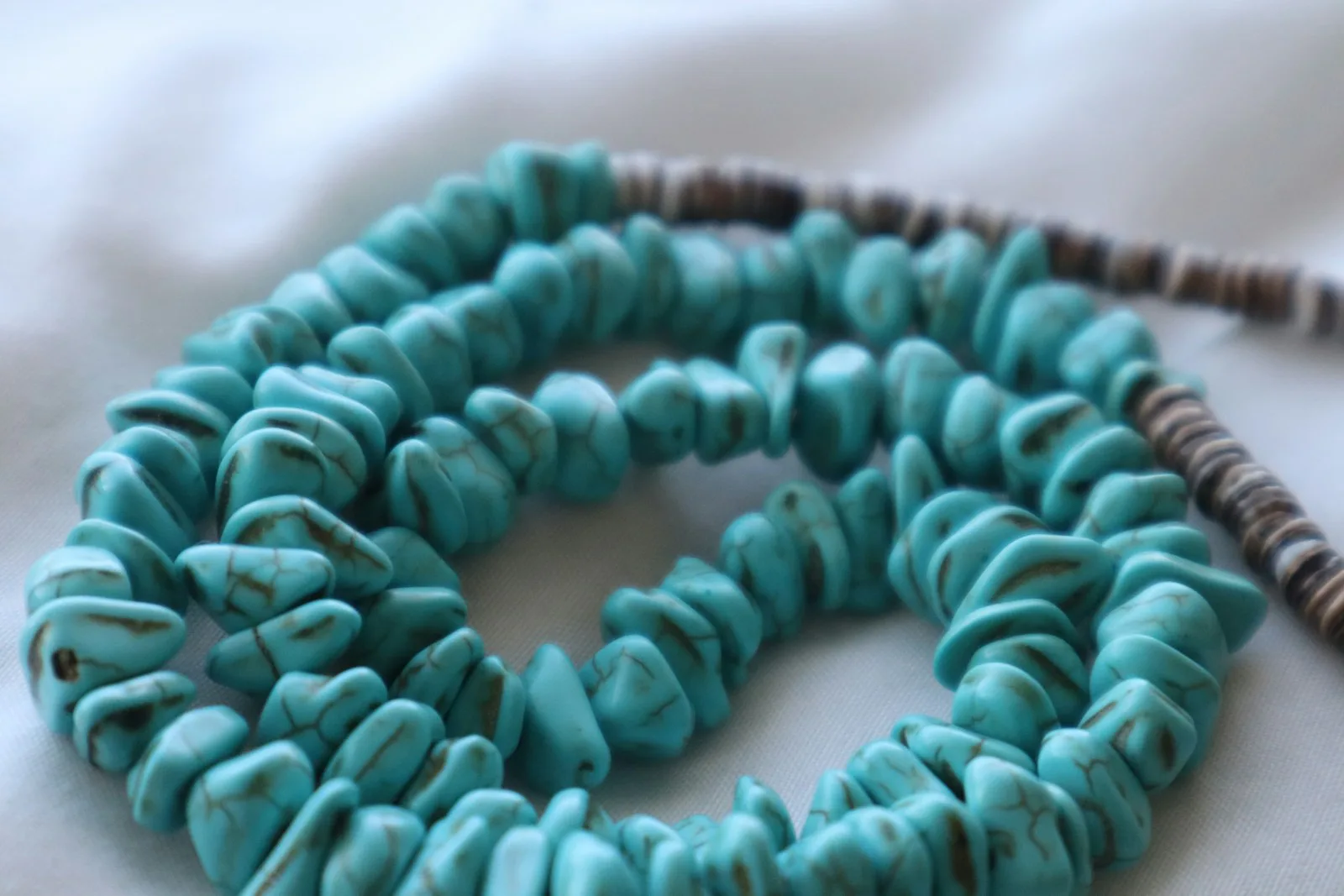Turquoise chunk necklace coiled on white bedding