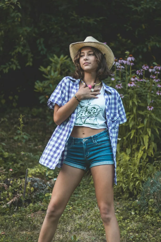 Gingham shirt with denim shorts and a straw hat in the garden