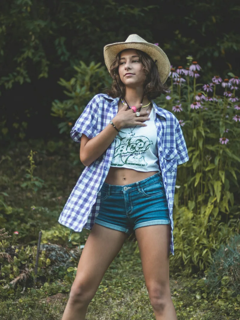 Gingham shirt with denim shorts and a straw hat in the garden